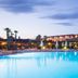 Garden Toscana Resort in San Vincenzo with illuminated outdoor pool at dusk and resort buildings beyond