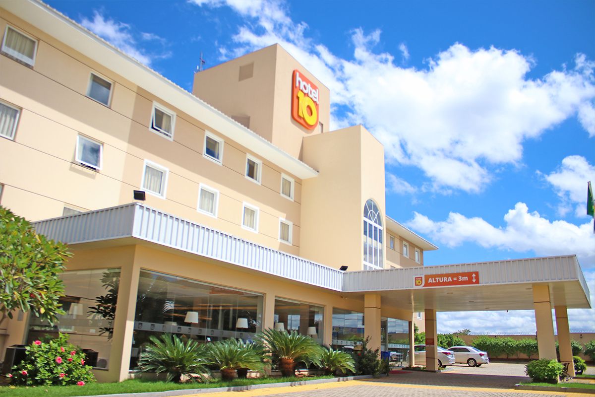 Strassen Hotel in Goiânia with covered entrance, landscaping, and blue sky