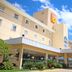 Strassen Hotel in Goiânia with covered entrance, landscaping, and blue sky