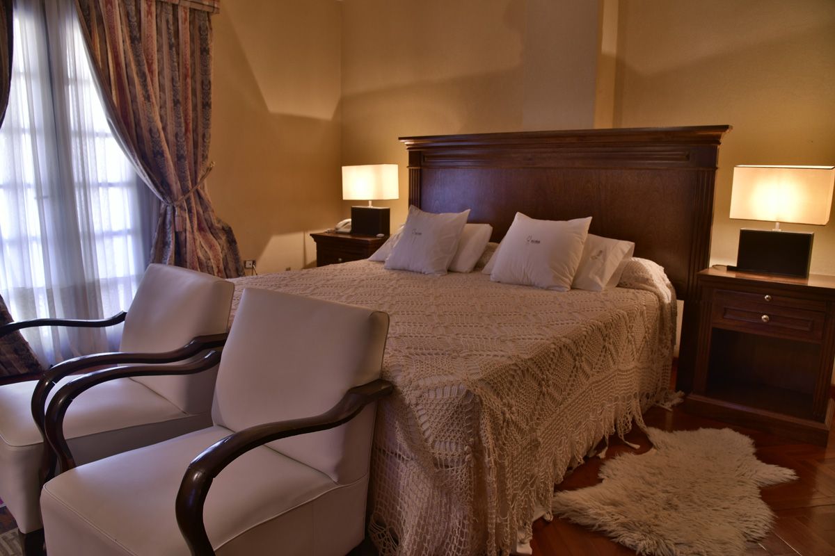 Villa Vicuña Wine & Boutique Hotel in Cafayate guest room with king bed, armchairs and bedside lamps