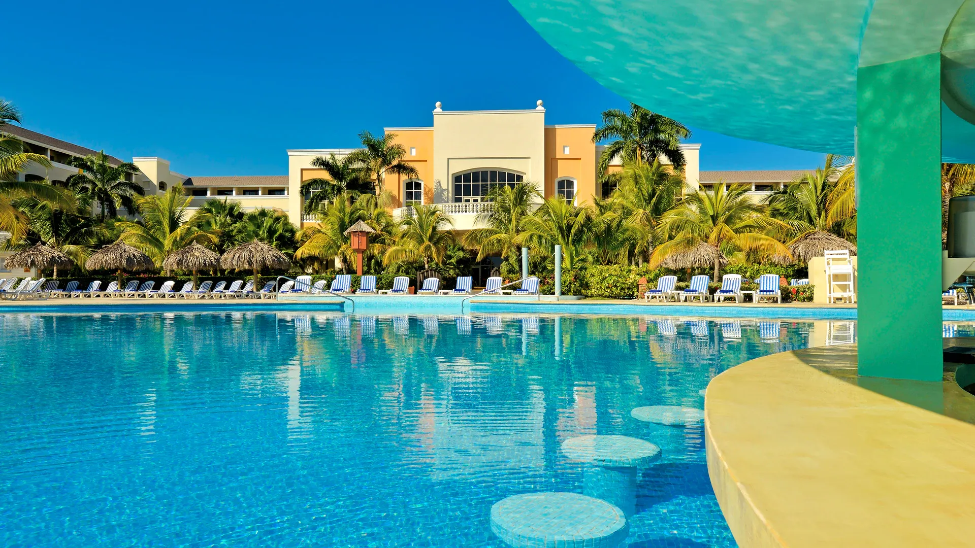 Iberostar Waves Rose Hall Beach in Montego Bay with a large outdoor pool and palm trees