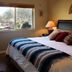 Cozy Cactus Sedona guest room with bed, dresser and large window overlooking desert greenery