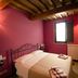 Diana House in Ripa guest room with magenta walls, double bed, and wood-beam ceiling
