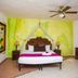 Hotel & Spa Xbalamqué Cancún room with carved bed, bright mural walls, and ceiling fan in Cancún