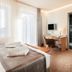 Parkhotel IV Jahreszeiten Kühlungsborn room with bed, desk, TV, and balcony doors in Kuehlungsborn