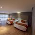 El Diplomatico hotel room in Mexico City with two beds, desk, and large window with city light.