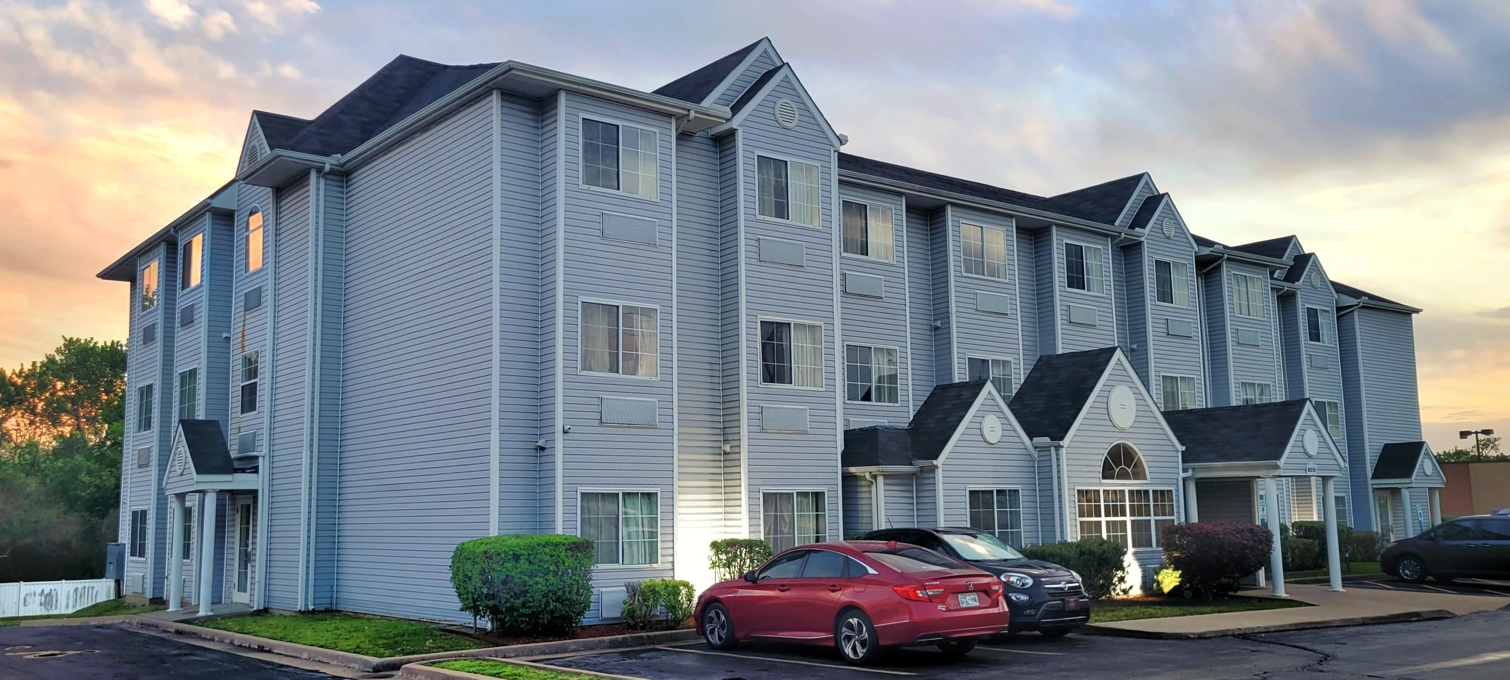 Microtel Inn & Suites by Wyndham Tulsa / Catoosa Route 66 exterior at sunset with parked cars in Tulsa