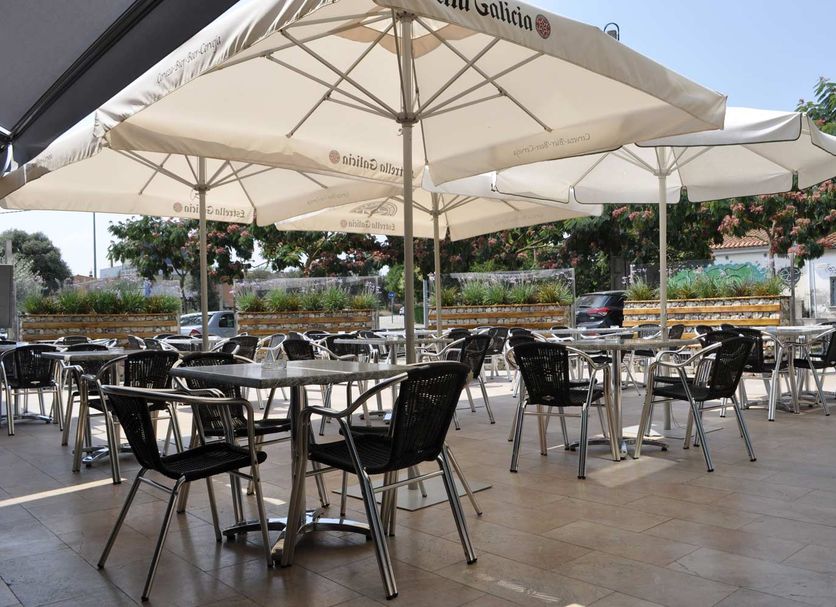 Hotel Palau de Girona terrace with outdoor café tables and large umbrellas in Sarrià de Ter