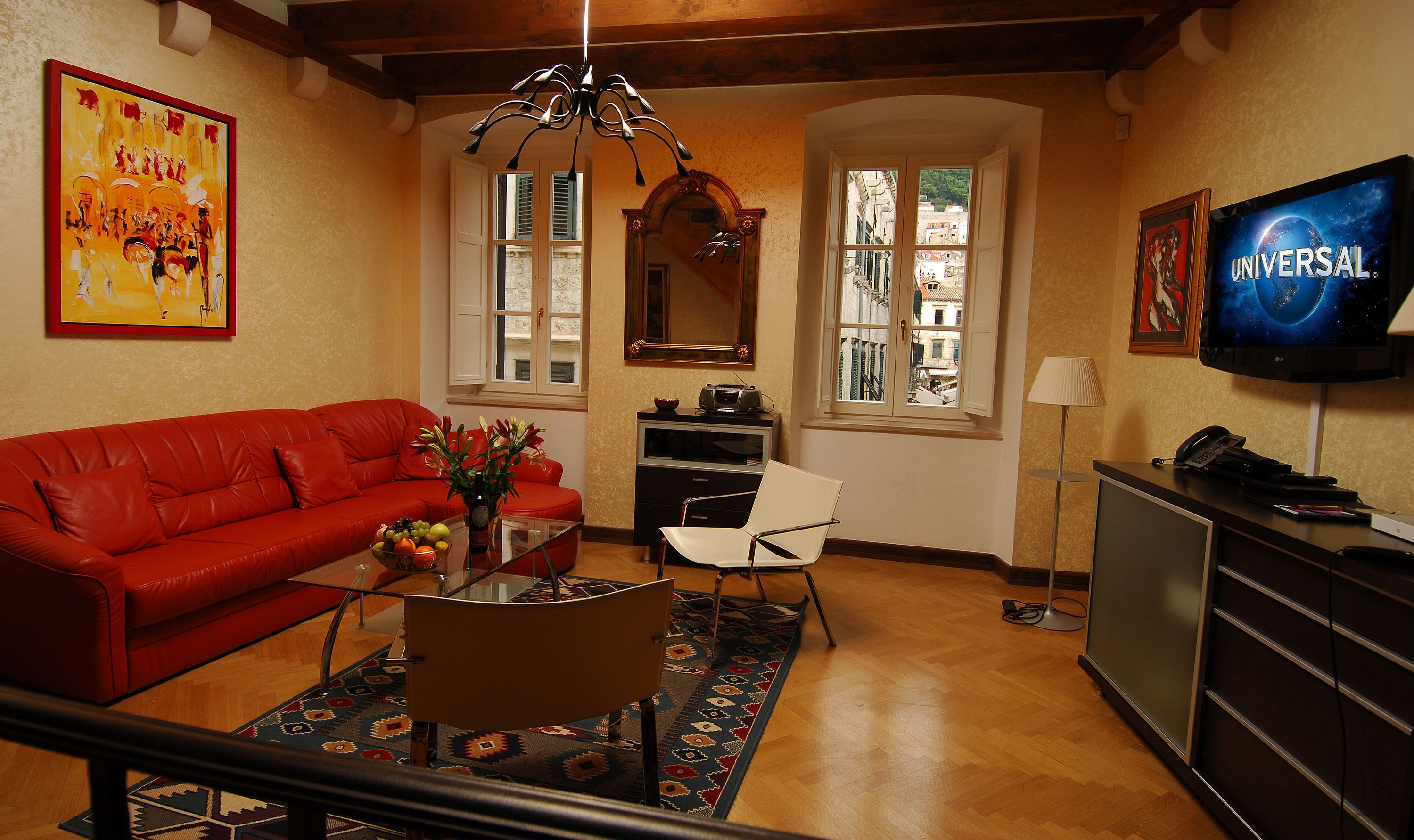 Celenga Apartments in Dubrovnik living room with red sofa, coffee table, windows, and wall-mounted TV