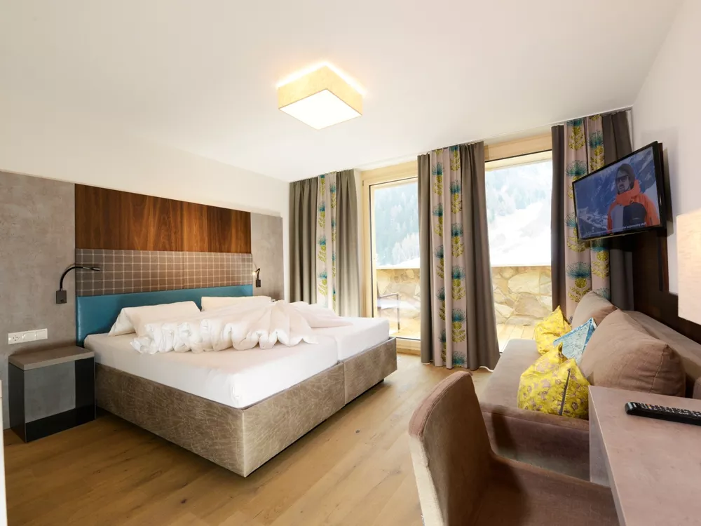 Hotel Nassereinerhof room in Sankt Anton am Arlberg with balcony doors, king bed and wall-mounted TV