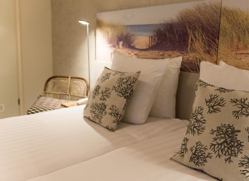 France Hotel Amsterdam guest room with twin beds, beach-themed headboard art and coral-pattern pillows