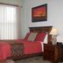 Canyon Rose Suites in Bisbee bedroom with red bedspread, nightstand lamp, and framed sunset art.