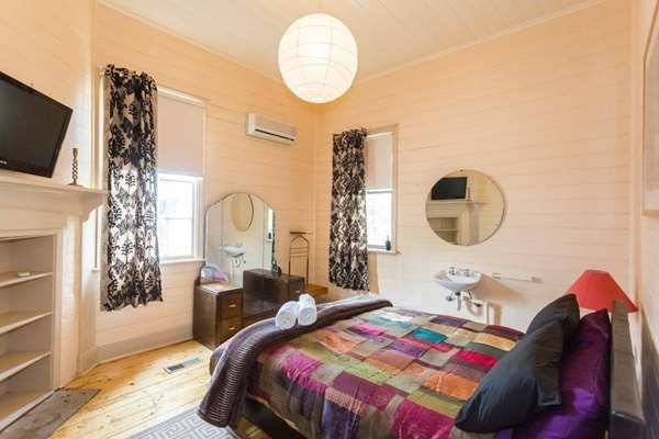2 Dukes Daylesford guest room with colorful quilted bed, round mirror, and fireplace in Daylesford