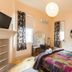 2 Dukes Daylesford guest room with colorful quilted bed, round mirror, and fireplace in Daylesford