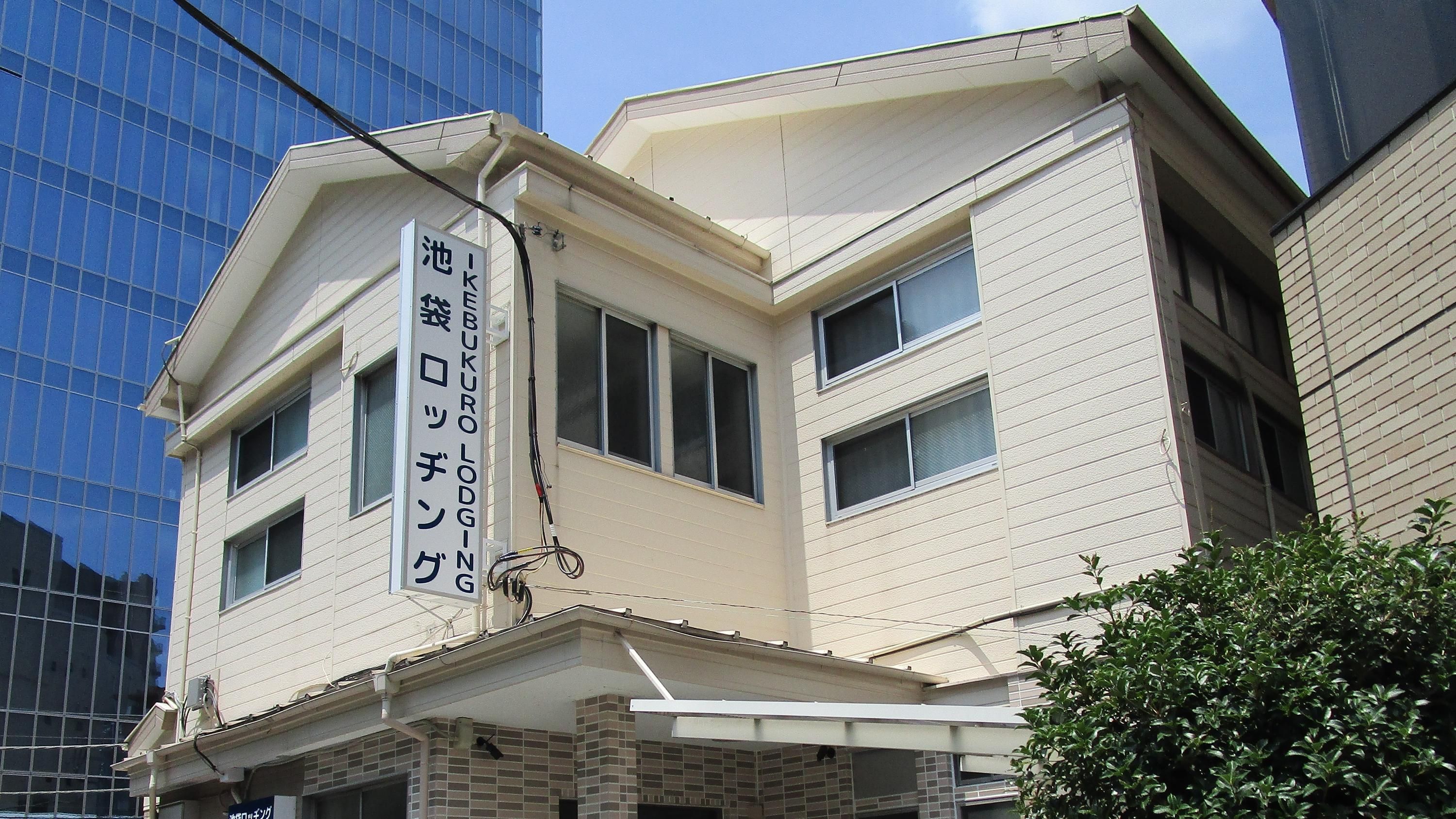 Ikebukuro Lodging in Tokyo, exterior of a white multi-story building beside a glass office tower