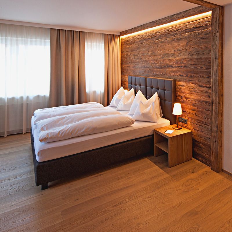 Pfefferkorn's Hotel in Lech am Arlberg: cozy double room with wood-paneled wall and bedside lamp