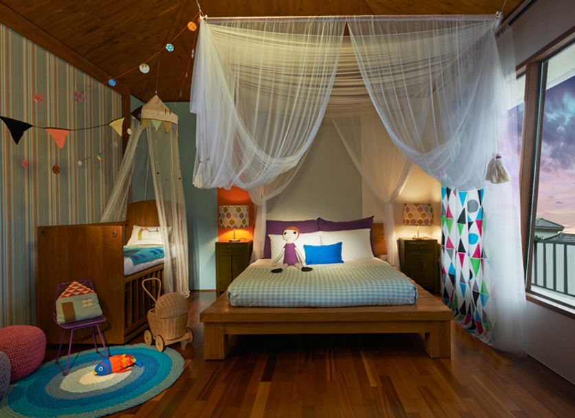 Olle Resort in Jeju City guest room with canopy bed, colorful decor, and balcony ocean view