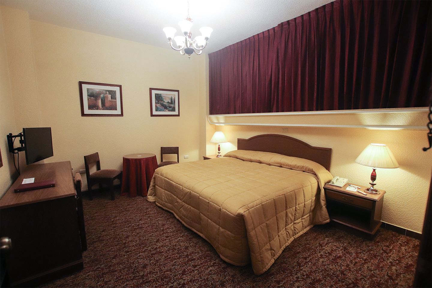 Montecarlo in Tampico guest room with king bed, desk, TV, lamps, and framed wall art