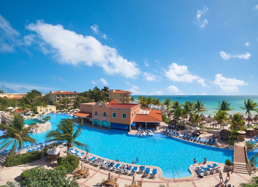 Hotel Marina El Cid Spa in Puerto Morelos with a large lagoon-style pool beside the beach and palm trees