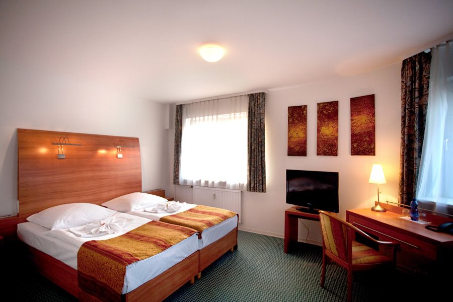 Hotel Kaiser in Berlin guest room with twin beds, desk, TV, and large window