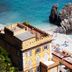 Hotel Meublè Agavi in Monterosso al Mare overlooks a beach with umbrellas and a rocky sea stack.