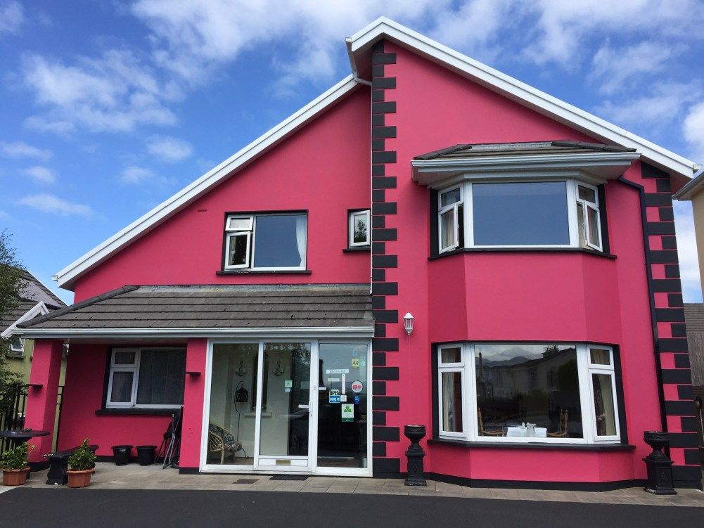 Muckross Drive House in Killarney, bright pink hotel exterior with bay windows and glass entrance