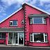 Muckross Drive House in Killarney, bright pink hotel exterior with bay windows and glass entrance