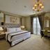 Amaroossa Royal Hotel Bogor guest room with king bed, chandelier, desk and French doors in Bogor