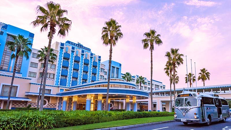 Disney Ambassador Hotel in Urayasu with palm trees, colorful facade, and a shuttle bus outside