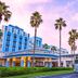 Disney Ambassador Hotel in Urayasu with palm trees, colorful facade, and a shuttle bus outside