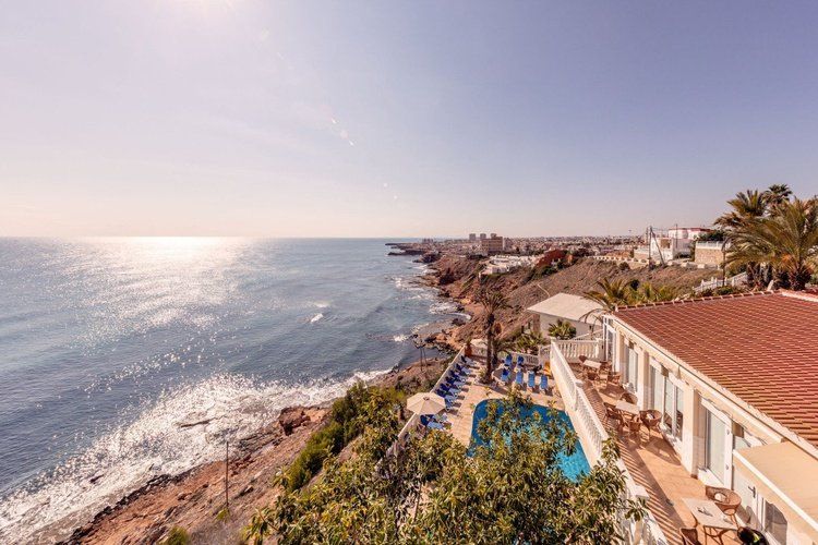 Hotel Masa International in Torrevieja with ocean-view pool and coastal cliffside scenery