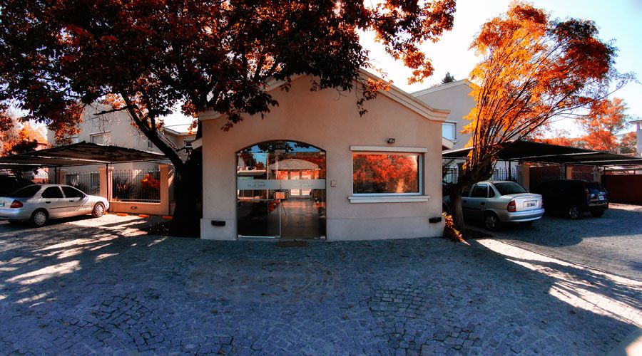 Pilar Apart in Pilar exterior with parked cars and autumn trees at the entrance