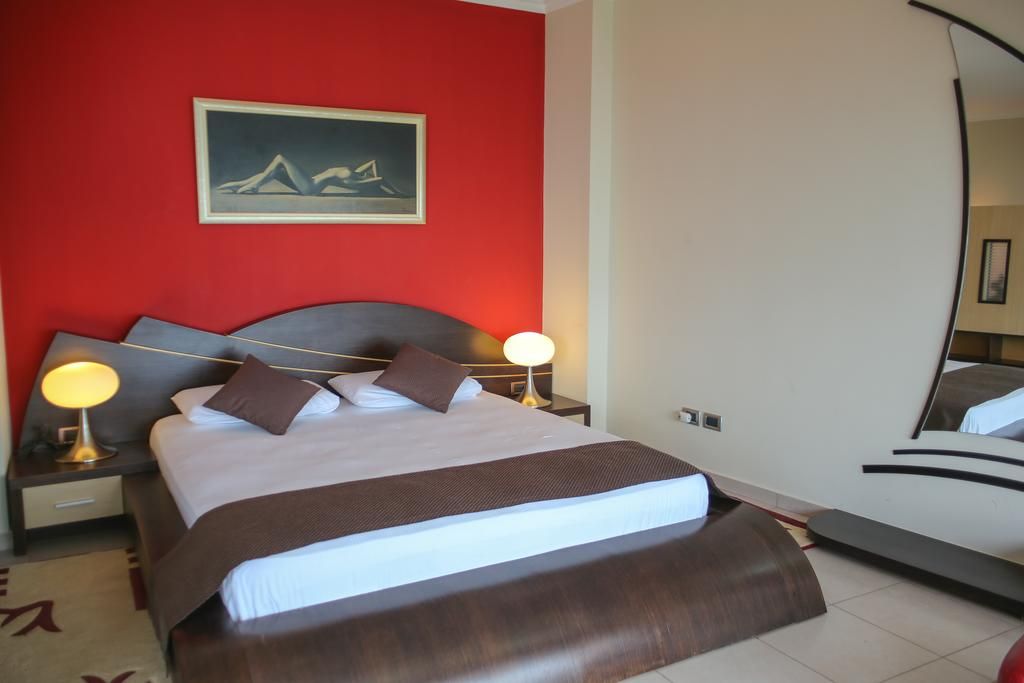 Hotel Liro - Adults Only room in Vlorë with red accent wall, double bed, bedside lamps and wall art
