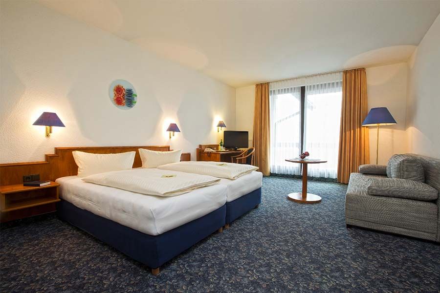Alpina Lodge Hotel Oberwiesenthal room with double bed, sofa, and balcony doors in Oberwiesenthal