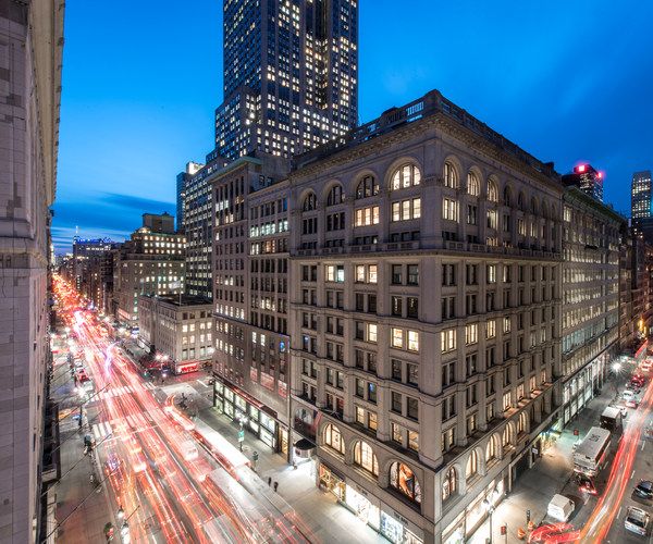 U Hotel Fifth Avenue in New York with city lights and traffic on a busy street at dusk