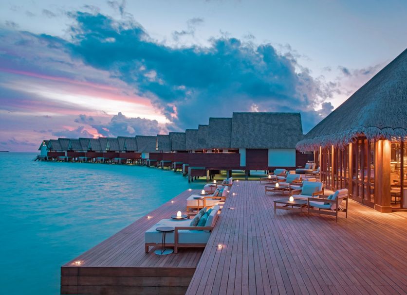 Heritance Aarah in Meedhoo: overwater deck with lounge chairs beside turquoise sea at sunset