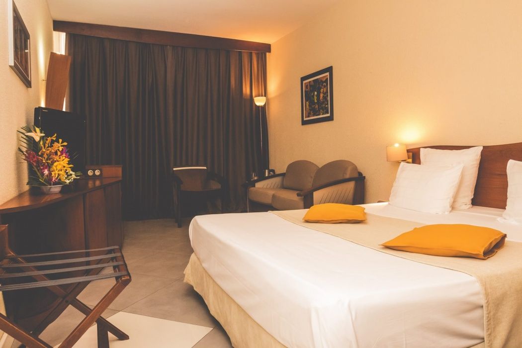 Hotel Des Roches in Kourou: guest room with bed, sofa, desk, and balcony doors