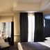 Hotel des Académies et des Arts, Paris guest room with striped chairs, wall-mounted TV, and balcony doors with curtains