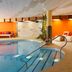 Hotel Nocturnes in Naturno indoor pool with orange lounge chairs and curved tiled seating area