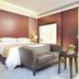 Shenzhen Nanshan L'Hermitage guest room with bed, sofa, side table, and warm wood-paneled walls in Shenzhen