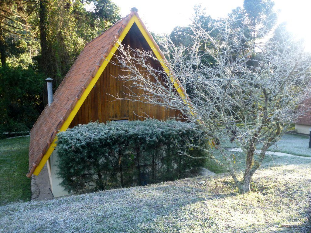 Pousada Passaredo in Gonçalves: A-frame cabin with steep roof, trees and frosty yard