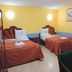 Hotel Real Tlaxcala room with two twin beds, yellow walls, and a small table in Tlaxcala